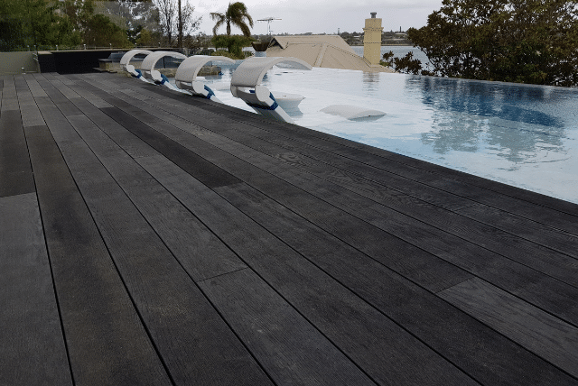 How Tradies Can Maximise Value with Millboard’s Low-Maintenance Decking 5 Concept Materials Composite Decking Dark grey low-maintenance decking surrounding a modern infinity pool