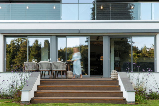 Low maintenance decking leads to patio with outdoor dining near sliding glass doors.