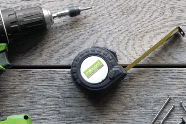 Drill, Millboard tape measure, and screws on professional decking installation.
