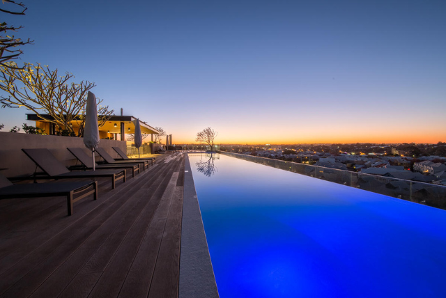 Rooftop infinity pool at sunset overlooking city lights, perfect for luxury outdoor spaces.