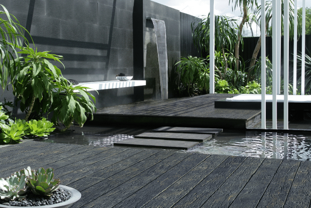 Modern garden with composite decking design, water feature, and lush plants.