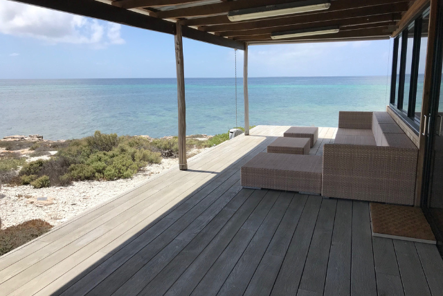 Coastal decking area with outdoor furniture overlooking the ocean. Build smarter projects with durable decking using the best decking material for long-lasting performance and style, designed for Australian conditions.