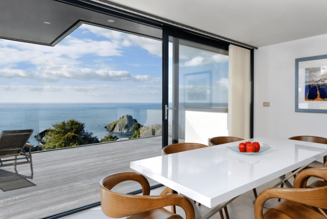 Premium Deck Solutions: A Global Journey with Millboard 1 Concept Materials Composite Decking Modern dining room with deck and ocean view, featuring Premium Deck Solutions.