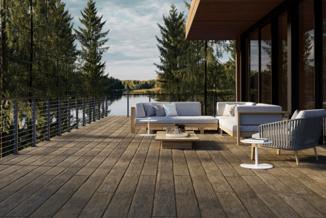 Luxury outdoor living deck with comfortable furniture overlooking a serene lake and forest.
