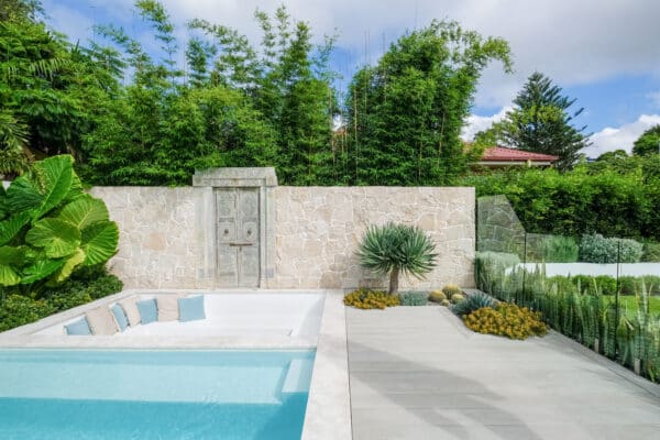 Luxury outdoor living space with a modern pool, stone wall, and bamboo.