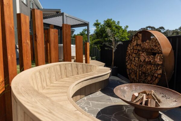 Curved wooden bench and fire pit in a luxury outdoor living space.